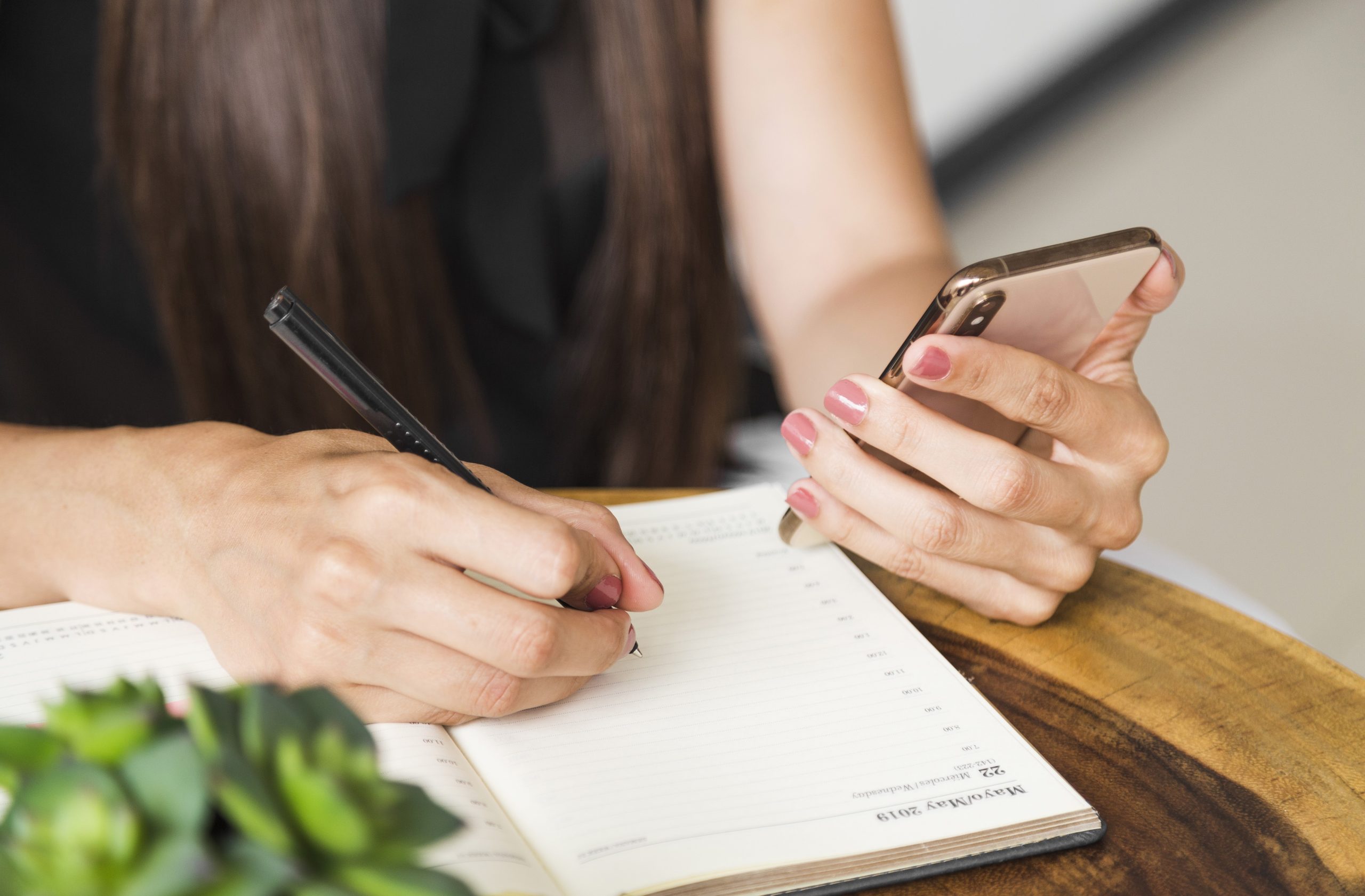 Closeup of woman taking notes illustrates blog "Do Project Managers Take Meeting Minutes?"