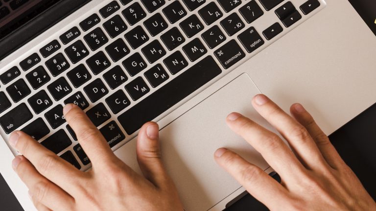Closeup of person writing on laptop illustrates blog "Mastering Writing Skills for Project Managers"