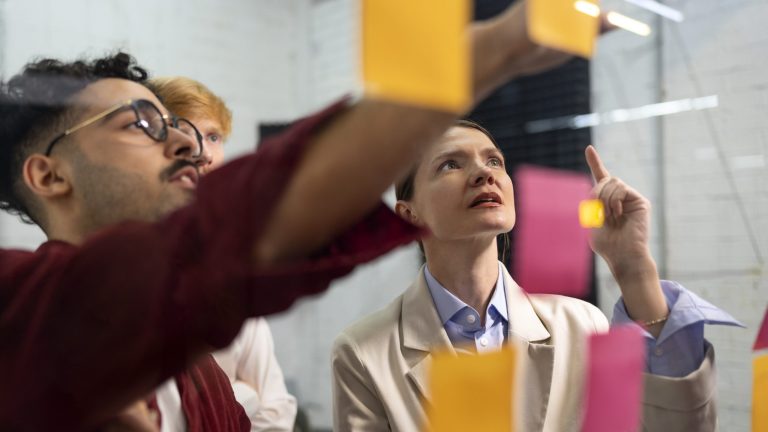 Team looking at clear wall wit post its.